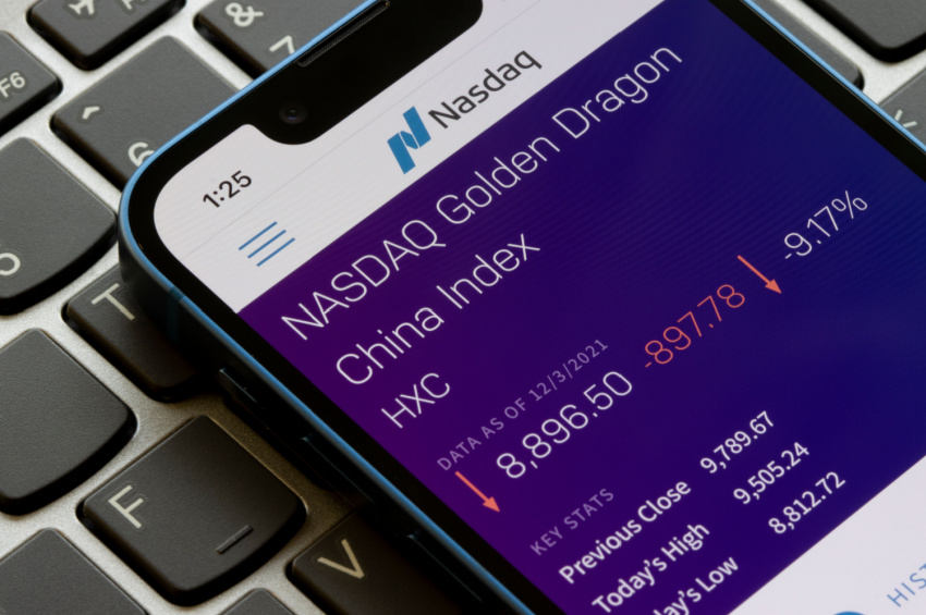 A close up of view of phone with Nasdaq news, placed above a keyboard.