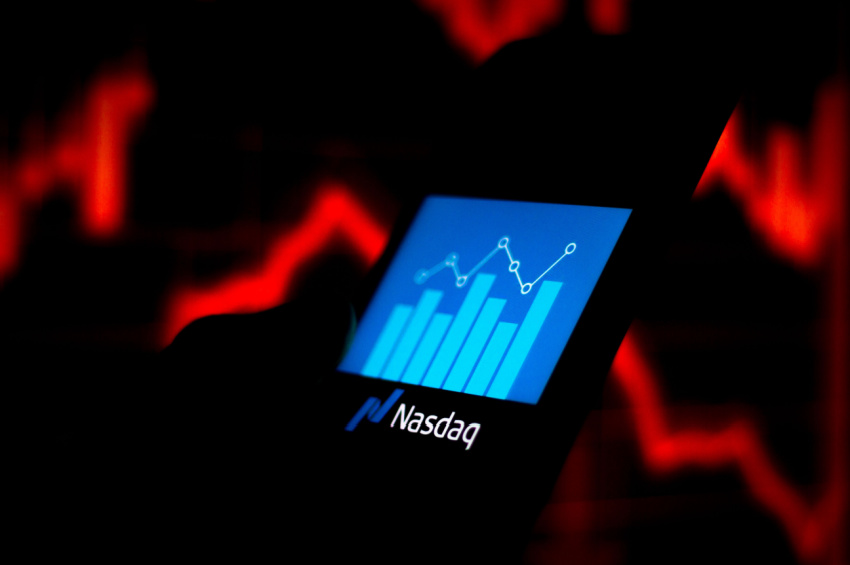 The Nasdaq logo seen displayed with a stock growth bar chart on a smartphone illustrates the risks & consequences of Nasdaq delisting.