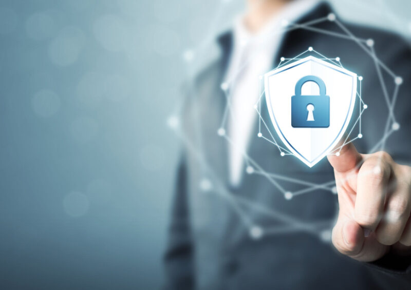 A businessman touching a shield protect icon illustrates the concept of fraud prevention in trade finance.