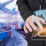 Image of a businessman holding a tablet on a world map with logistic import and export background for Supply Chain Financing With CBDC.