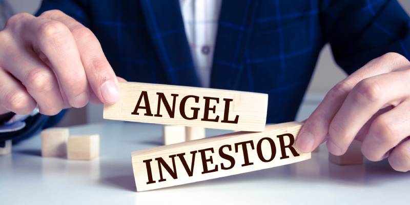 A businessman holding wooden blocks with words 'Angel investor'