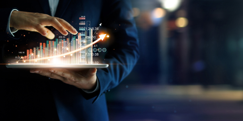 A businessman holding tablet analyzing stock data and stock growth graph.