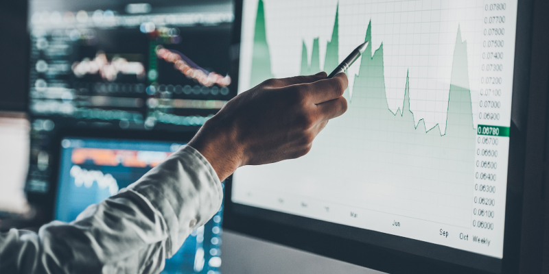 Close-up image of a young businessman pointing on the data presented in the chart with pen analyzing Q4 data.