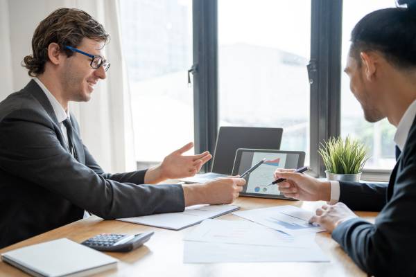 Financial advisor pointing at graph shown on a tablet giving advice to an investor.