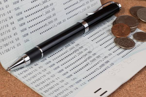 Few coins and a pen kept on a bank passbook indicating general banking.