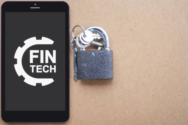 A mobile phone displaying fintech logo kept near a lock and key indicating security.