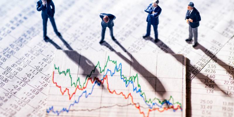 Businessmen standing on stock market charts analyzing stock market data and graphs.