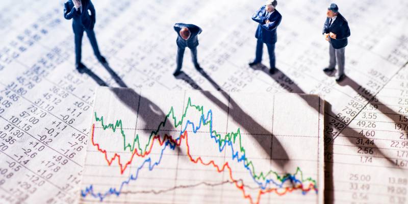 Businessmen standing on stock market charts analyzing stock market data and graphs.