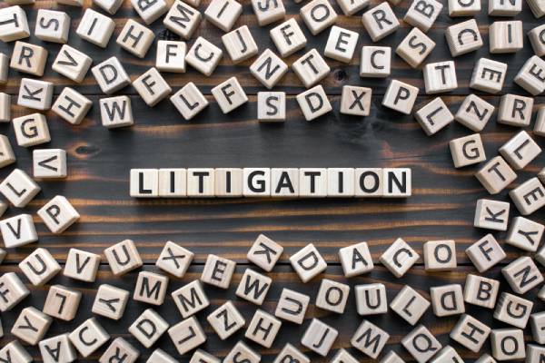 The word litigation arranged on a table with blocks and random letters of blocks spread around it.