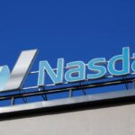 Image of a roof sign board of NASDAQ on a building along with the logo.