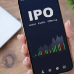 A female hand holding a phone with IPO stocks purchase app on screen.