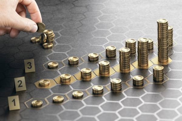 Image of a human hand stacking coins in 3 different groups indicating different portfolios and investor decisions.