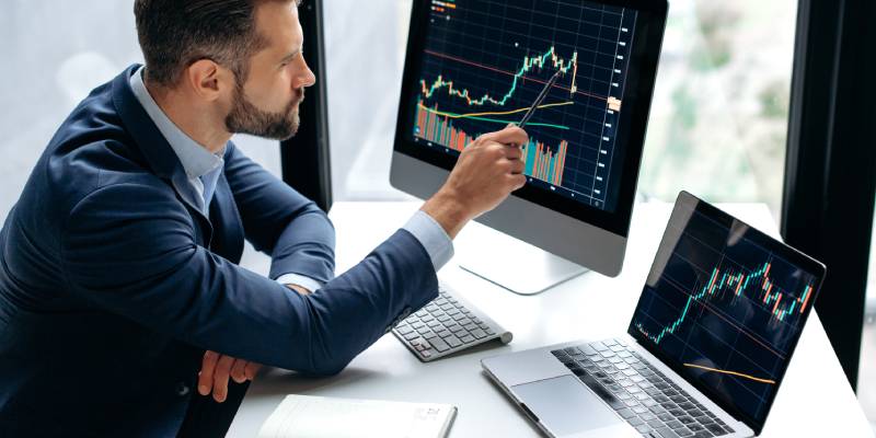 An investor using computer and laptop,displaying trading data of a stock.