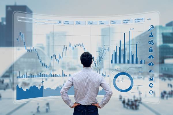 Rear view of a person analysing stock market indicators along with financial data and charts displayed on the virtual screen in front of him.