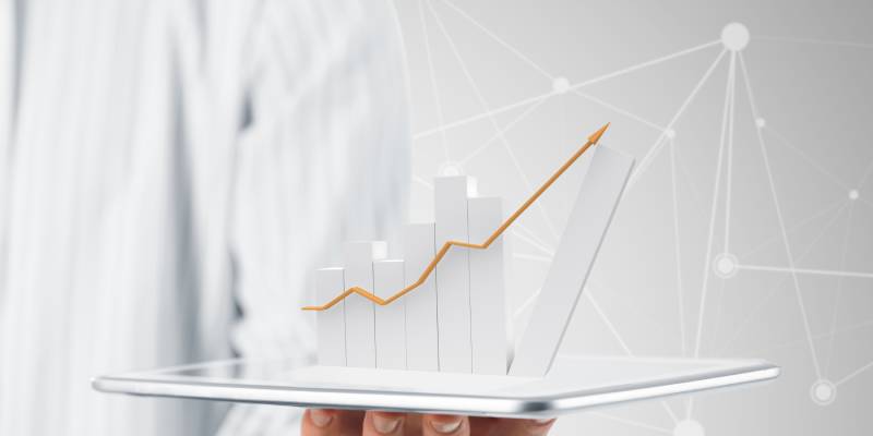 Image of a person holding a tab on his hand with the data and graph of a stock above it.